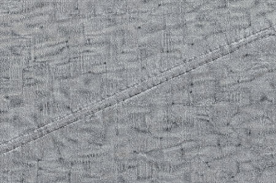 Macro of heather grey cotton jersey showing knit texture and tonal depth across a topstitched seam